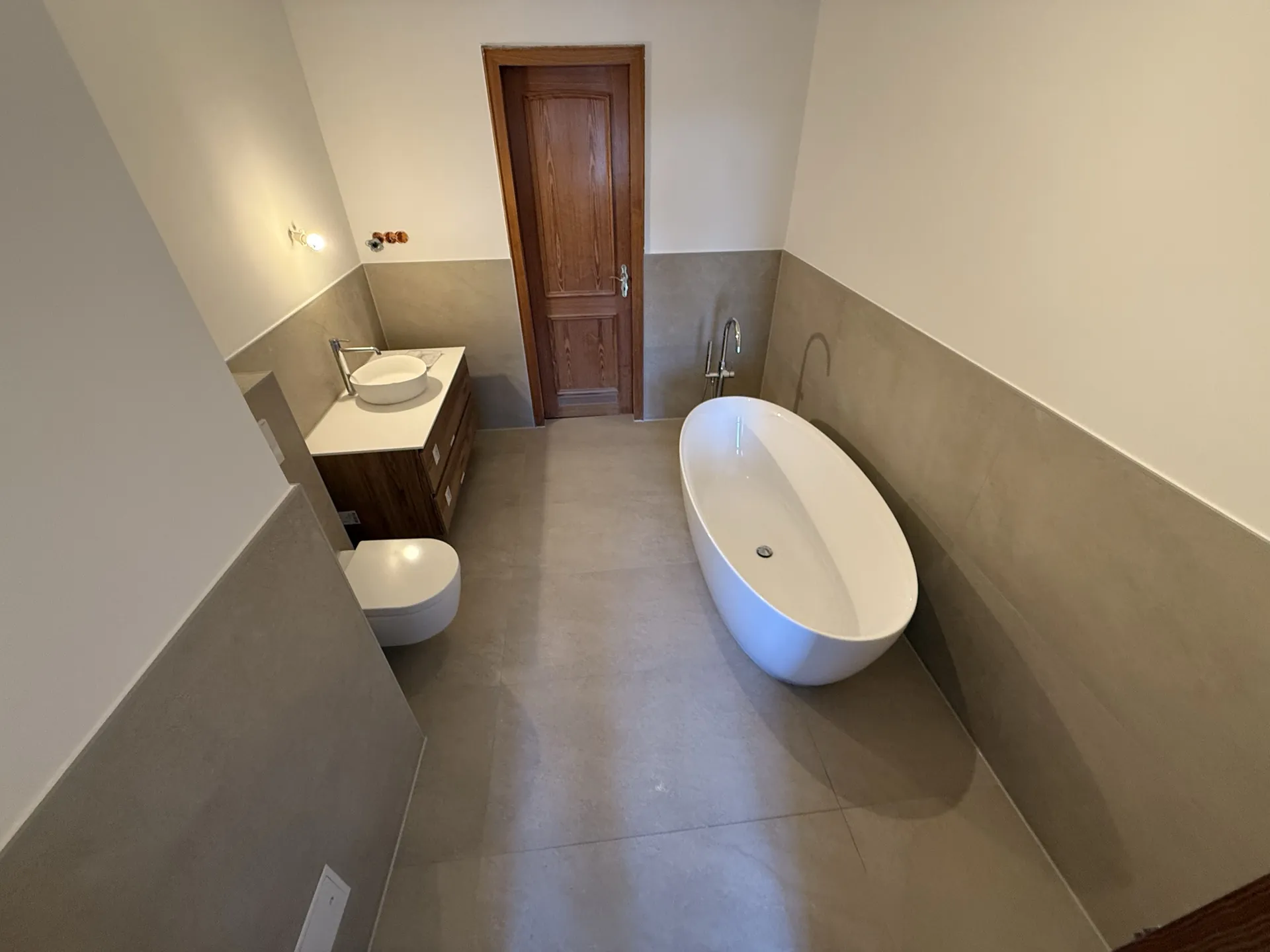 Badezimmer Seitenansicht mit freistehender Badewanne und Holztür — Badsanierung Mülheim