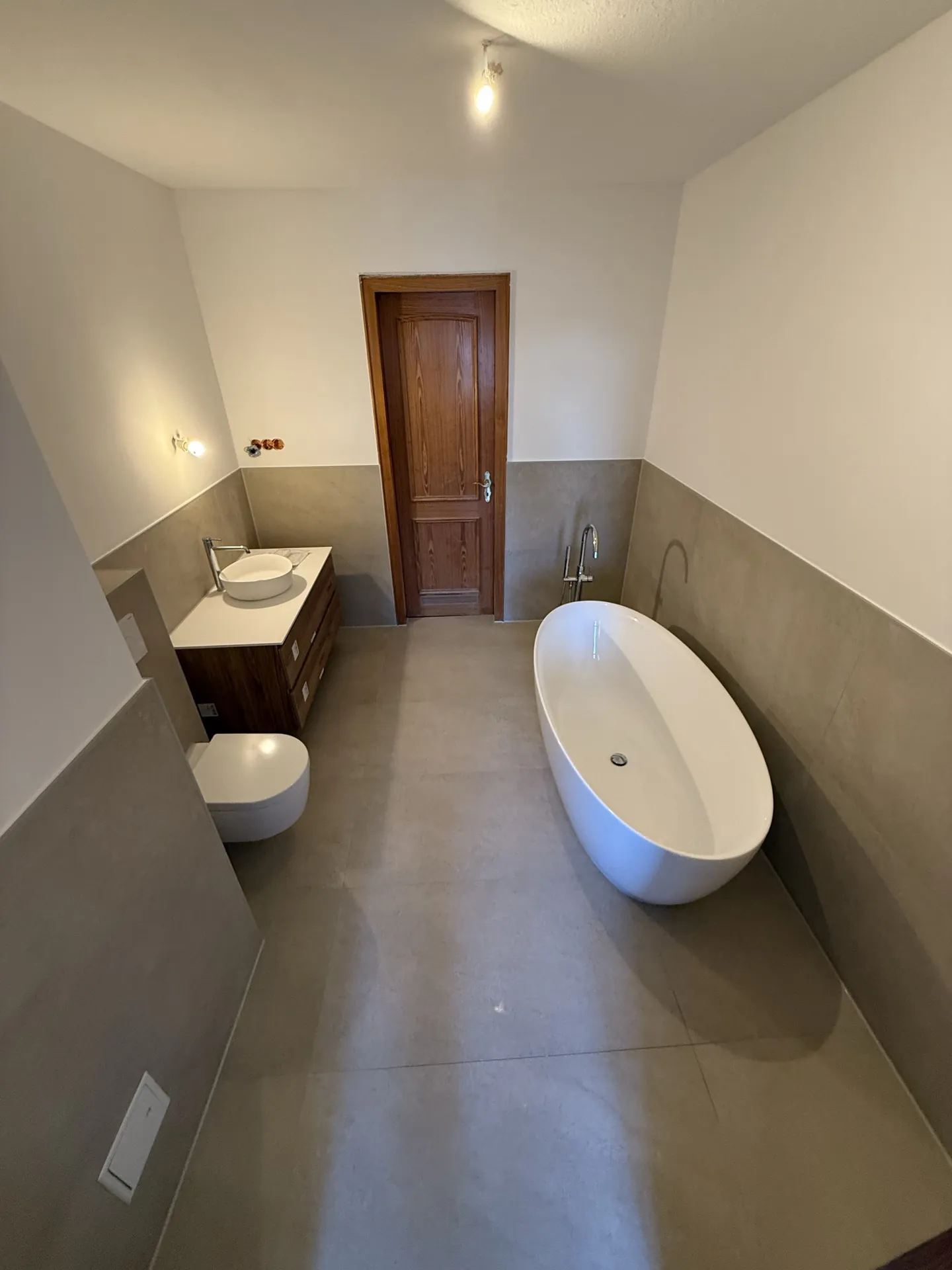 Badezimmer Weitwinkelansicht mit Großformat-Fliesen und Badewanne — EVENT Bau